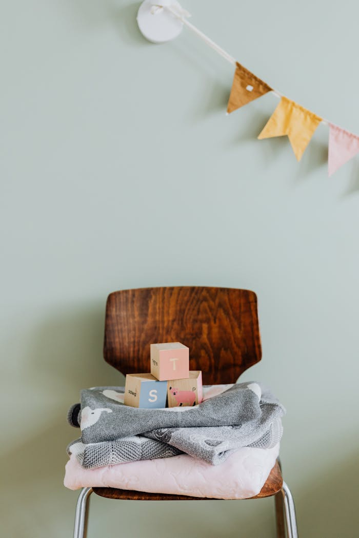 A quaint indoor nursery setup featuring a wooden chair, colorful building blocks, and a soft blanket.