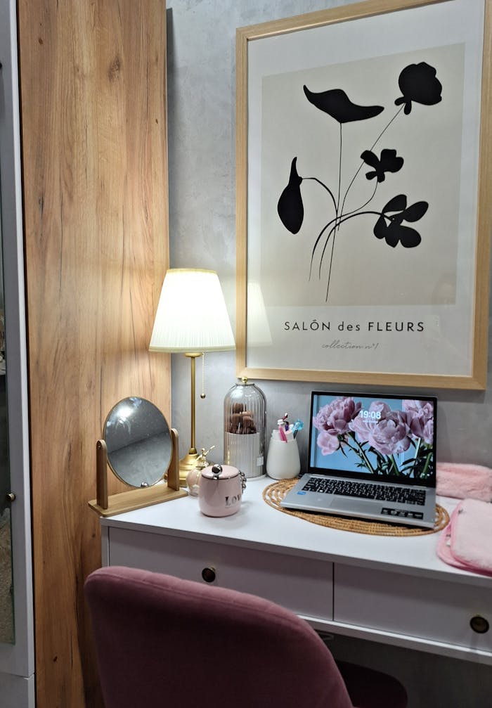 A cozy home workspace featuring modern decor, a wall art piece, and an open laptop with floral wallpaper.
